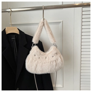 Detail of faux fur beige shoulder bag featuring silver star rivets and metal chain