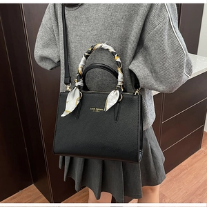 Detail view of black lychee leather tote bag with decorative scarf and gold logo