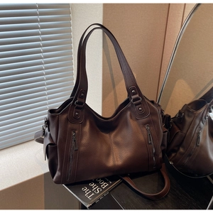 Close-up of brown litchi grain leather tote bag with vertical zippers and side pockets