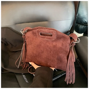 Detail of a brown suede handbag with fringe tassels and a silver metallic hardware clasp