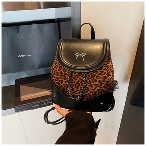 Détail du sac à dos léopard avec nœud métallique et bordure en chaîne sur cuir noir