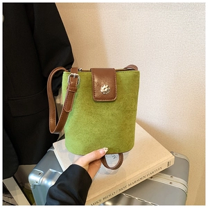 Detail of green suede mini bucket bag with brown leather strap and metal buckle