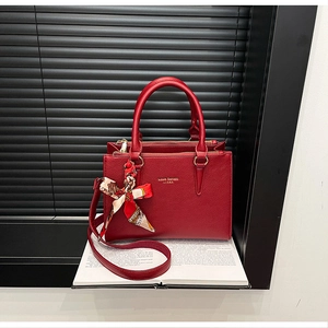Detail of red lychee grain leather tote bag with decorative silk scarf on the handles