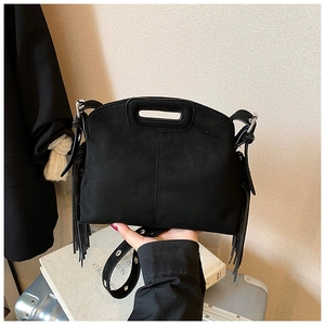 Detail of black faux suede handbag with side tassels and silver hardware accents