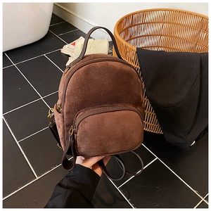 Detail view of brown suede backpack with faux leather straps and vintage gold zippers