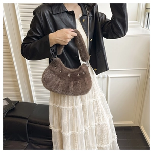 Sac hobo en peluche marron orné de clous en forme d'étoiles argentées porté à l'épaule