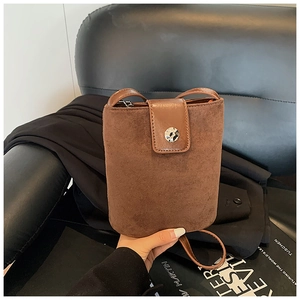 Detail of dark brown suede bucket bag featuring smooth leather flap and magnetic silver buckle