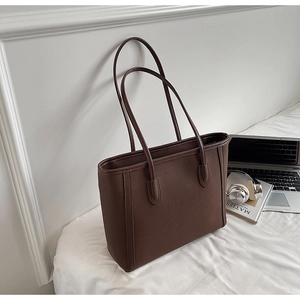Detailed macro view of brown pebbled leather tote bag in a casual lifestyle setting