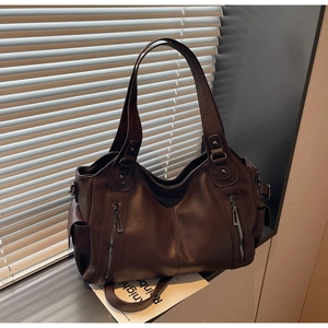 Detail of dark brown lychee texture leather tote bag with vertical zippers and side pocket