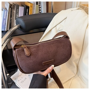 Detailed close-up of dark brown suede shoulder bag with gold zipper and embossed logo