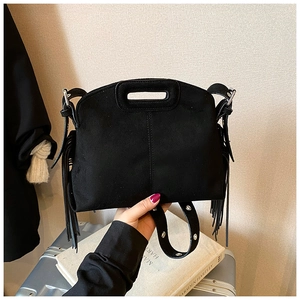 Detail of black faux suede handbag featuring vintage tassels and hollow cutout handle