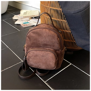 Detail of a brown suede mini backpack with vintage bronze hardware and leather straps