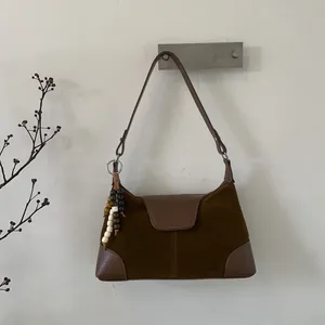 Detail of brown suede tote bag featuring a vintage patchwork design and wood bead tassel
