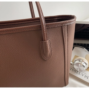 Close-up of lychee grain leather texture and stitching on dark coffee tote bag