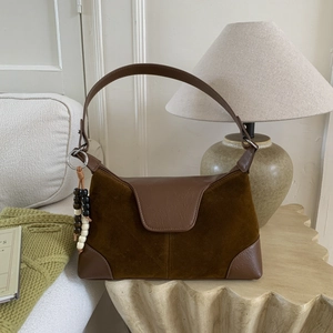 Detail showing mixed suede and smooth leather textures with retro beaded charm accent