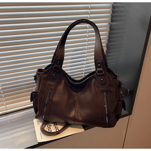 Detail of dark coffee leather tote bag featuring metal zipper pockets and grainy texture