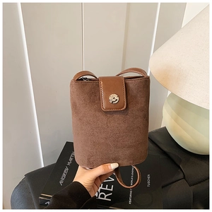Close-up of brown suede and smooth leather bucket bag with silver metal buckle detail