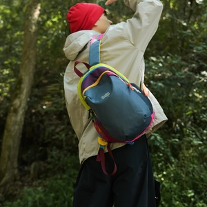 Outdoor shot of a colorful waterproof nylon crossbody bag worn during a forest hike