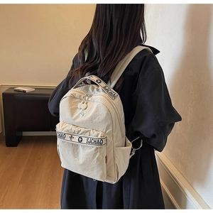 Detail of off-white nylon backpack featuring SJCHAO floral webbing on the front pocket