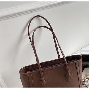 Detail of dark brown tote bag showing premium lychee grain leather and secure zipper