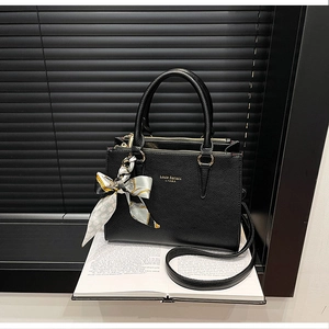 Detail of black pebbled leather tote with gold hardware and silk scarf on handle