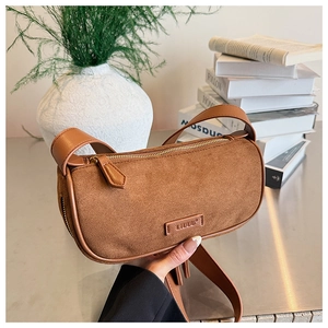 Detailed close-up of brown suede moon bag with gold zipper and minimalist brand logo