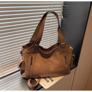 Macro shot of brown lychee grain leather tote bag with decorative zippers and side pocket