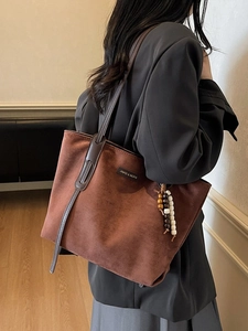 Dark brown suede-like large tote bag with elegant beaded charm shown on model