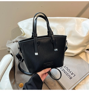 Close-up of black woven texture tote bag with silver hardware and detachable shoulder strap