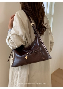 Dark brown glossy hobo bag with gold zipper and minimalist retro vibe on model