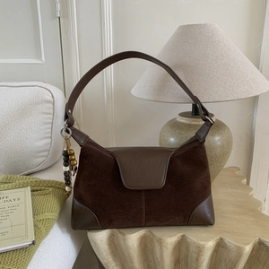 Detail of retro dark brown suede handbag with smooth leather trim and ethnic bead charm