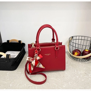 Close-up of red lychee leather tote bag with silk scarf and logo detail