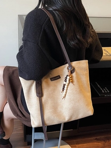 Beige suede tote bag with brown leather straps and wooden bead charm for daily commute