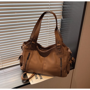 Detail of brown litchi pattern tote bag with vertical zippers and sturdy metal rivets