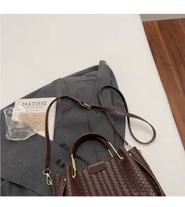 Detail of dark brown woven tote bag with smooth shoulder strap on a grey blazer