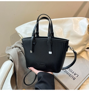 Detailed view of black woven texture tote bag with silver hardware and shoulder strap