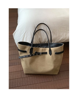 Detail of khaki suede tote bag with black leather handles and silver metal hardware