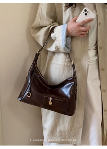 Close-up of retro dark brown leather tote with gold hardware and zipper detail