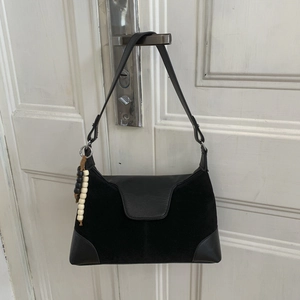 Detail of black suede patchwork shoulder bag with black and white beaded charm decoration