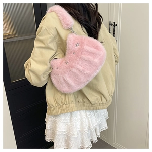Sac croissant en peluche rose avec clous étoiles argentés porté sur un manteau beige chic
