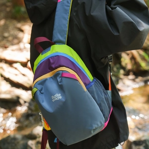 Outdoor back view of a colorful hiking chest bag with blue mesh pocket and brand logo