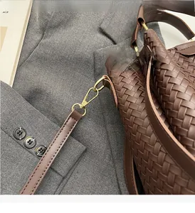 Detailed close-up of brown woven texture and shiny gold hardware on the bucket bag