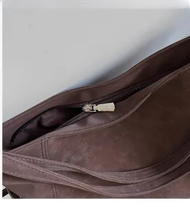 Detailed close-up of smooth silver metal zipper on vintage dark brown leather tote bag