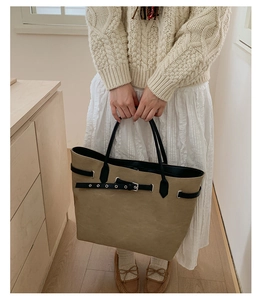 Detail view of khaki tote bag with adjustable black leather belt and silver metal buckle