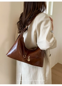 Detail of dark brown oil wax leather hobo bag with gold hardware and adjustable strap