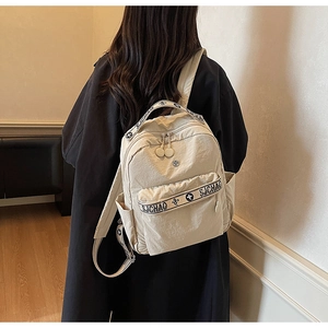 Detailed view of the beige nylon backpack with floral printed straps on a black coat