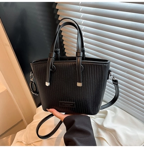 Detailed view of black woven texture leather bucket bag with silver hardware and logo plate