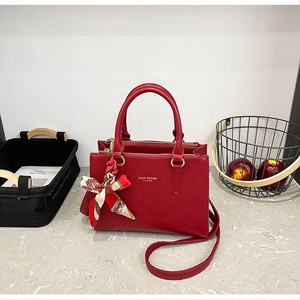 Detailed macro view of dark red lychee leather texture and golden metal logo on the handbag