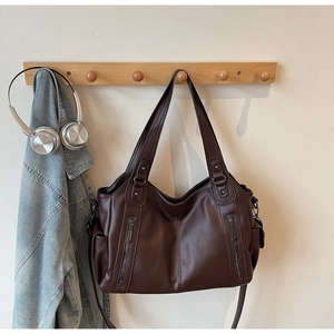 Detailed view of dark brown pebbled leather tote bag with functional front zippers and side pockets