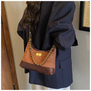 Close-up of brown suede and patent leather crossbody bag with chain and diamond quilting